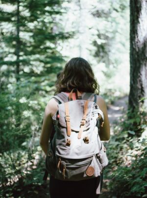 woman in sleeveless top and backpack surrounded by trees during daytime