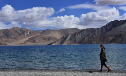 woman wearing jacket walking on seashore during daytime