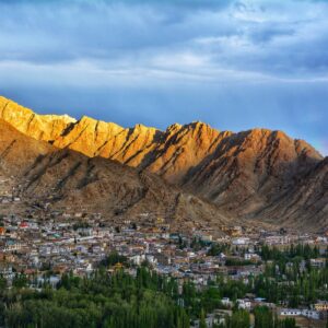 green trees near brown mountain under white clouds during daytime